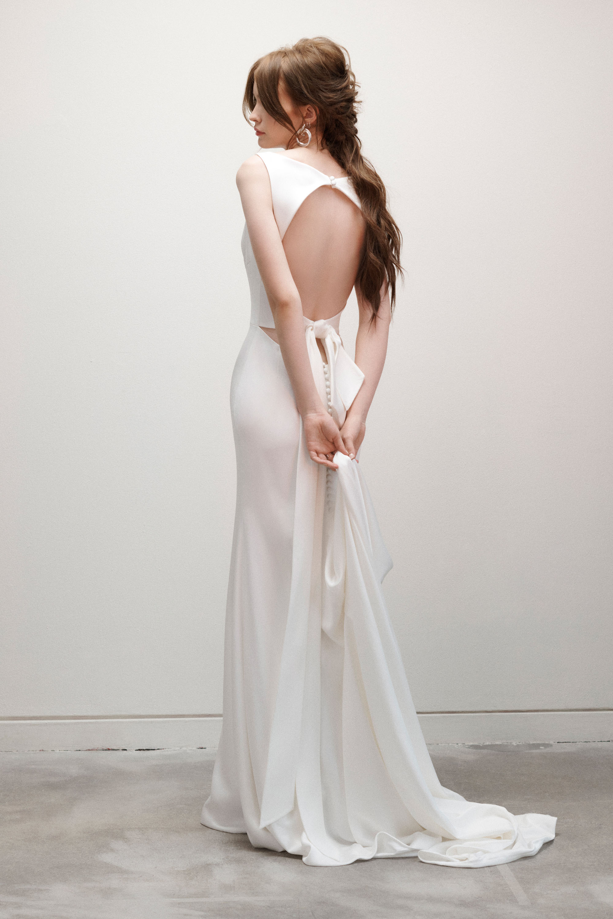 Bride wearing the Twiggy sheath gown from the back, showing the open back and couture bow.