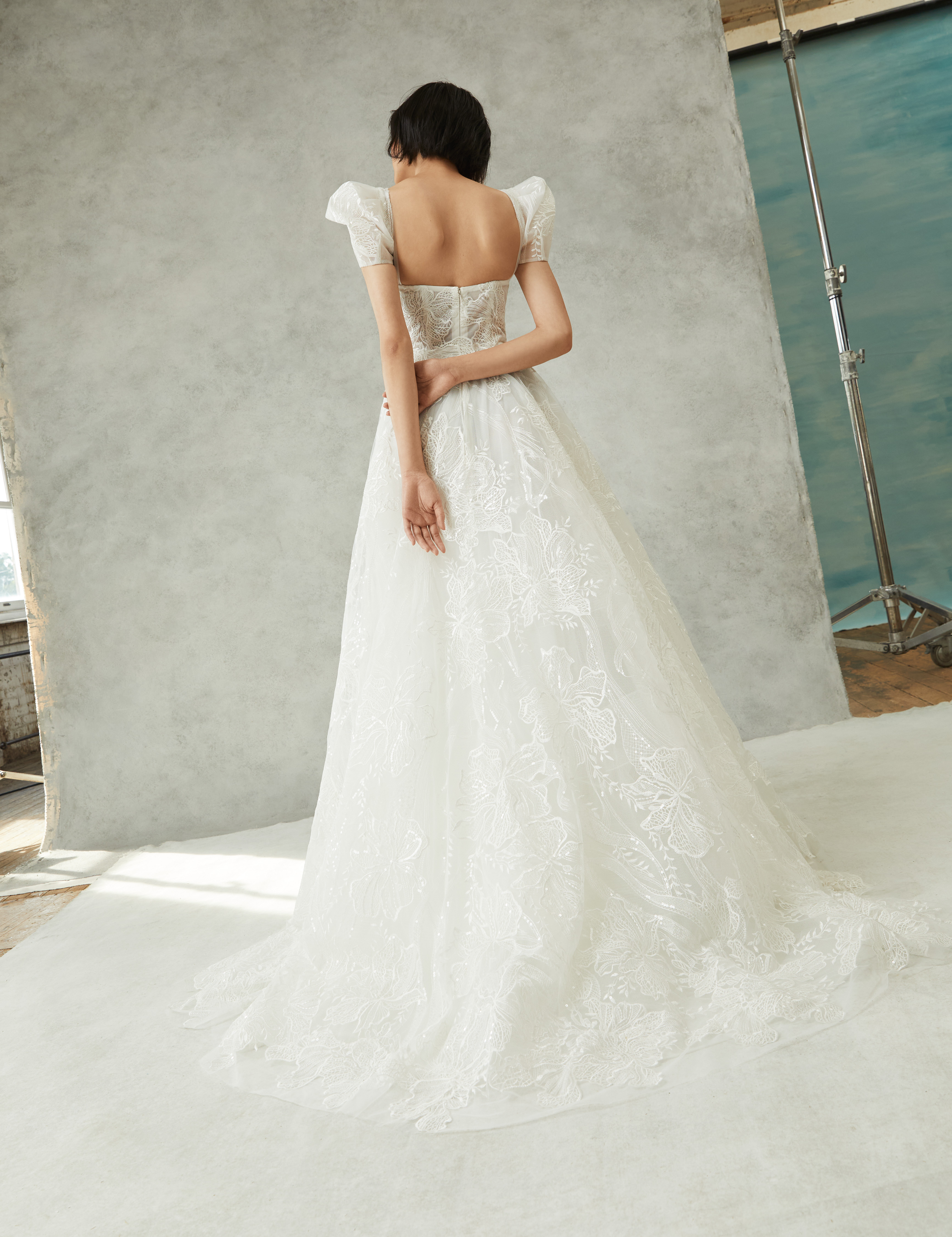 Back view of Sofie ivory ball gown with detachable puff sleeves, floral embroidered shimmer lace, and tiered skirt.