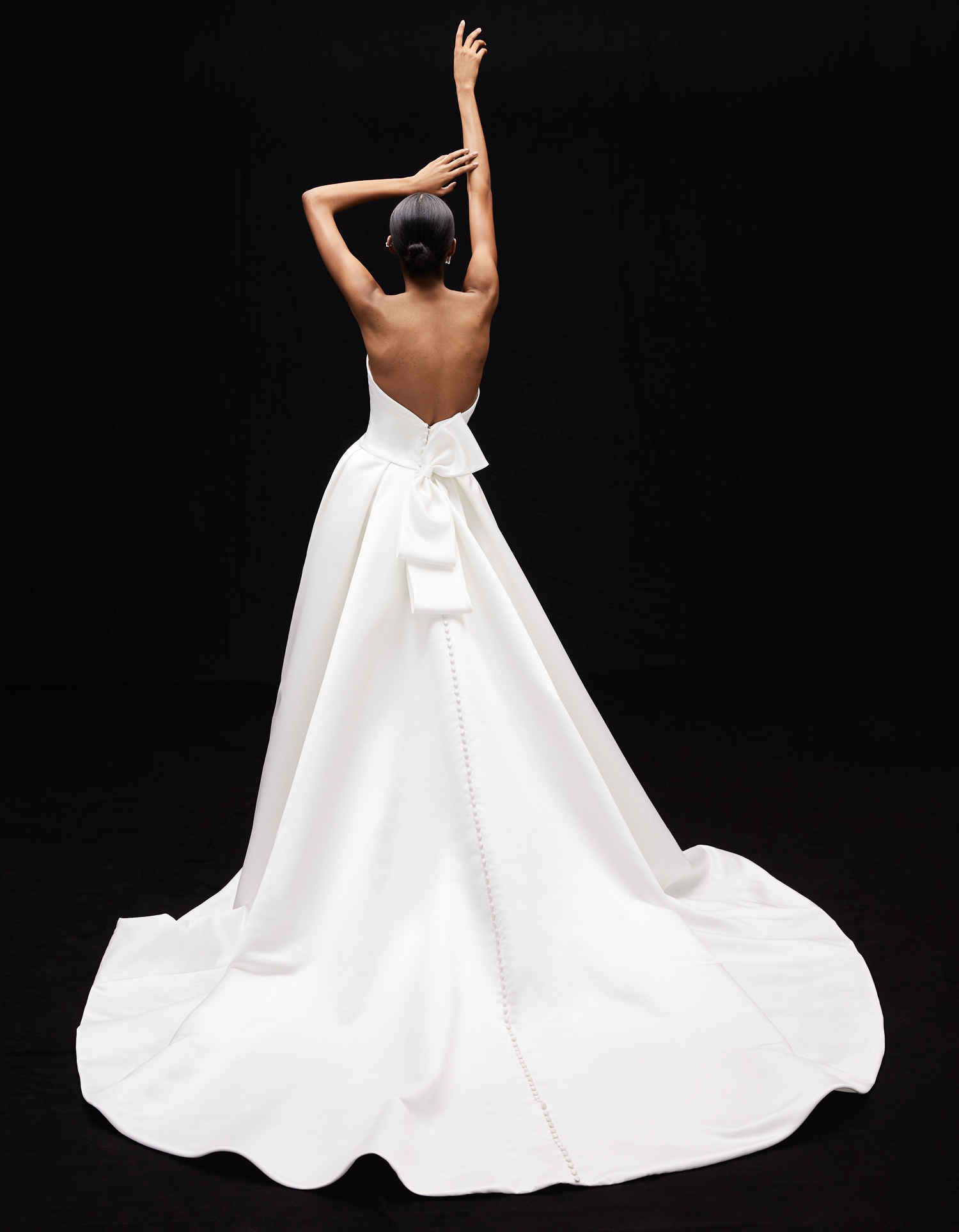 Back view of Demi satin ball gown with tuxedo bow, draped corset bodice, and full skirt.