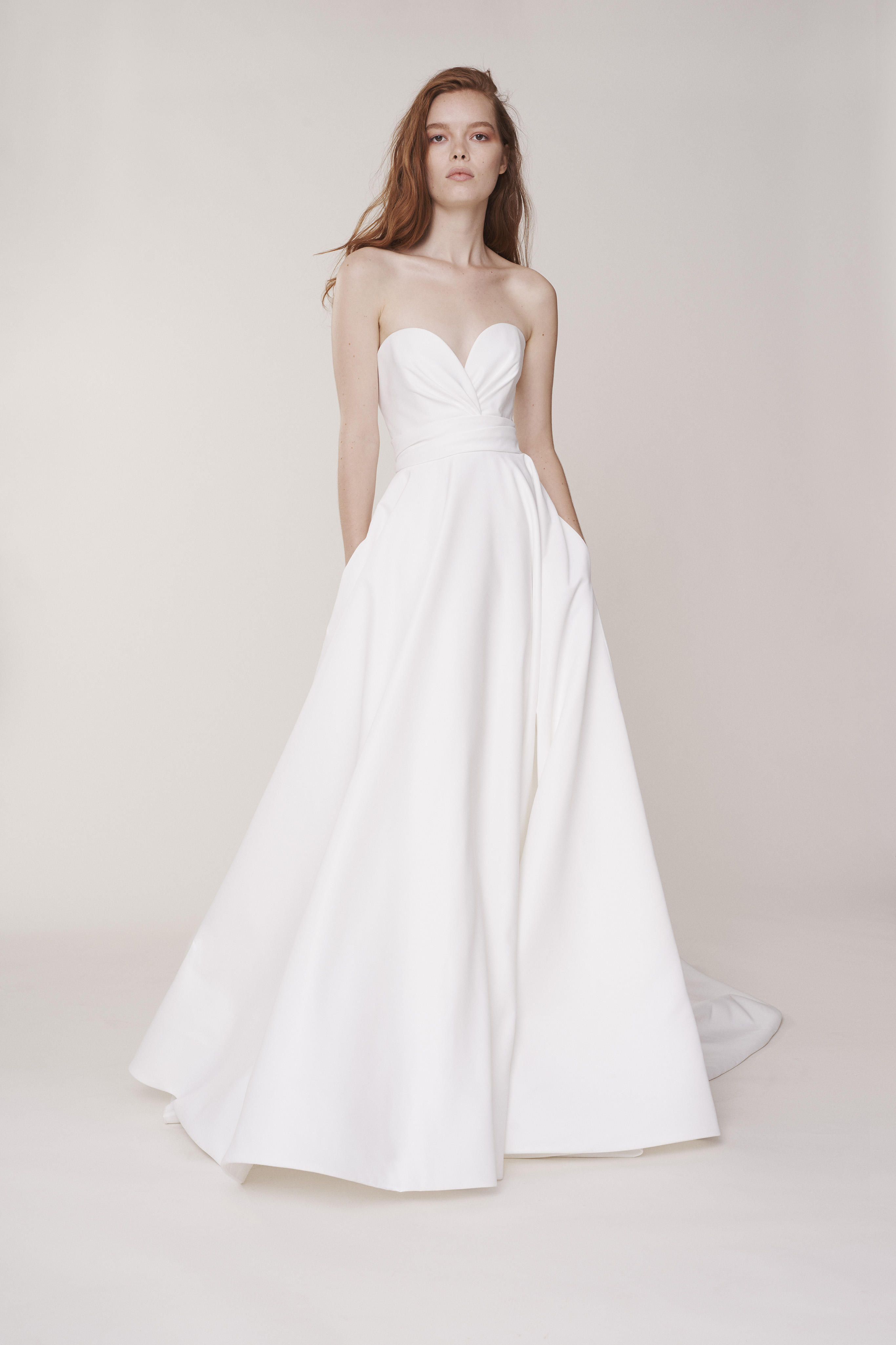 Ashford ivory matte satin ball gown with cross-over draped sweetheart bodice and pockets, shown from the front.