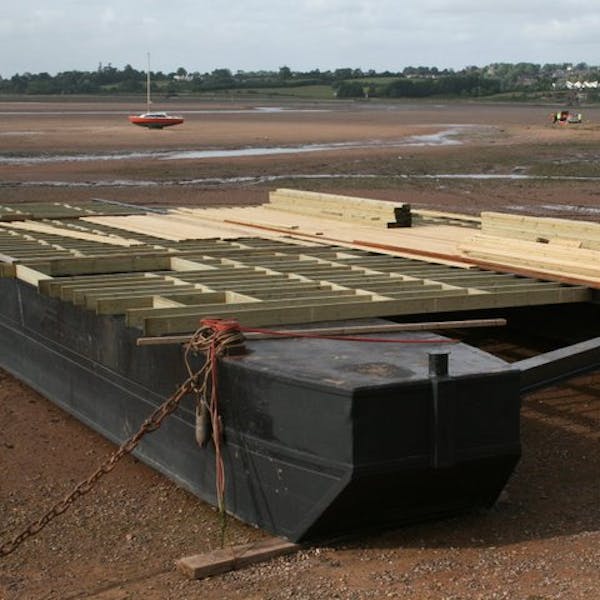Timber decking being built atop the two joined barges