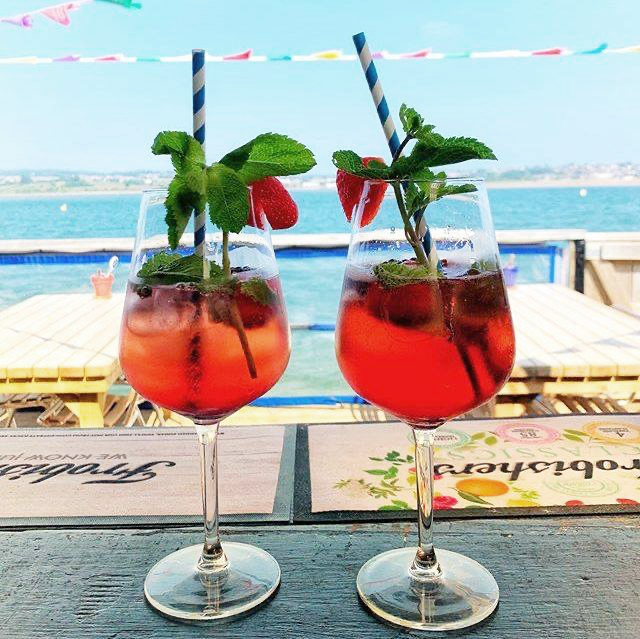 Two cocktails on the bar, looking out towards the estuary on a sunny day