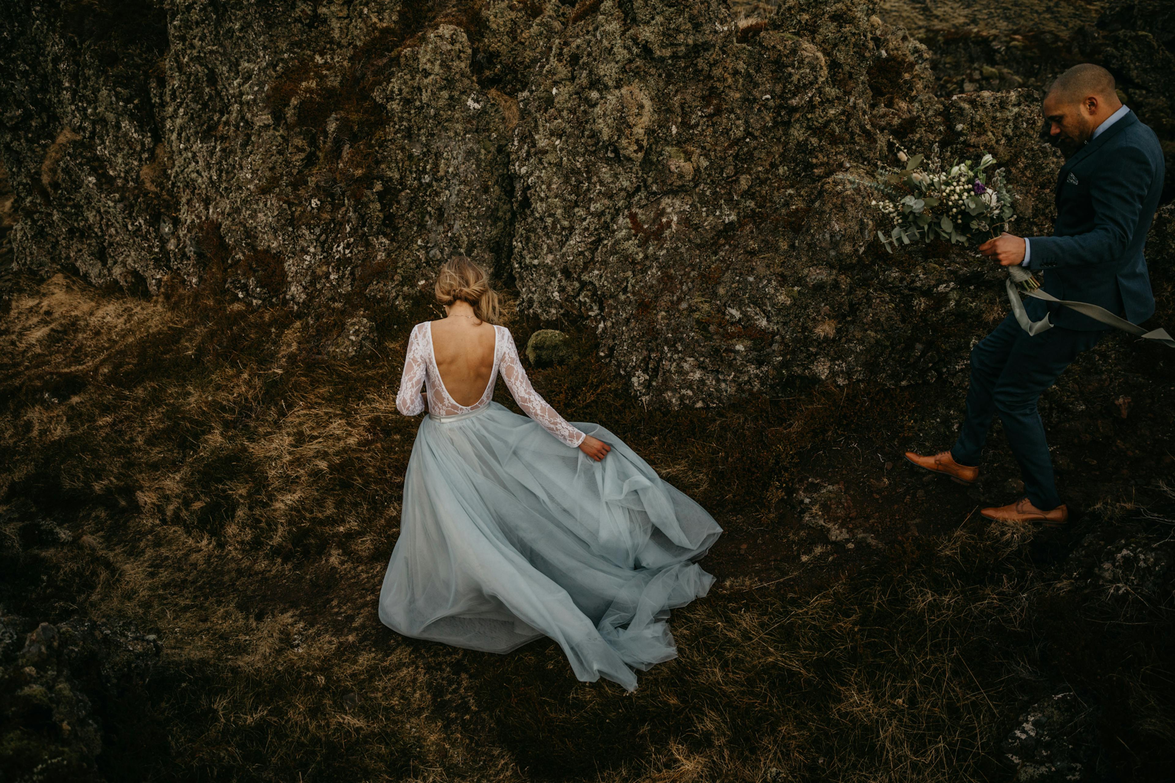 Bride and groom walk on rocks in Iceland