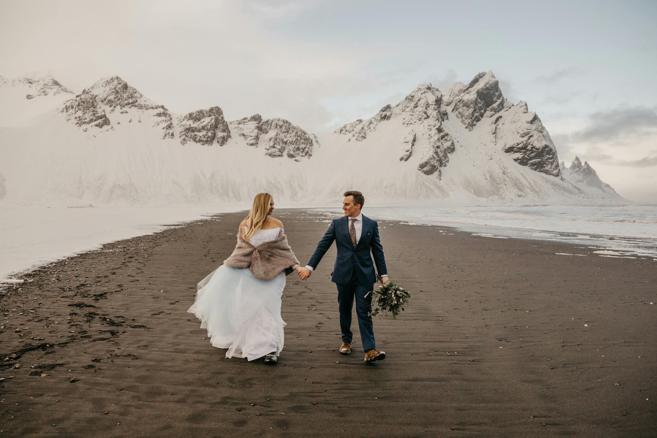 Bride and groom in a winter beach landscape at Vestrahorn mountain in Stokksnes, Iceland