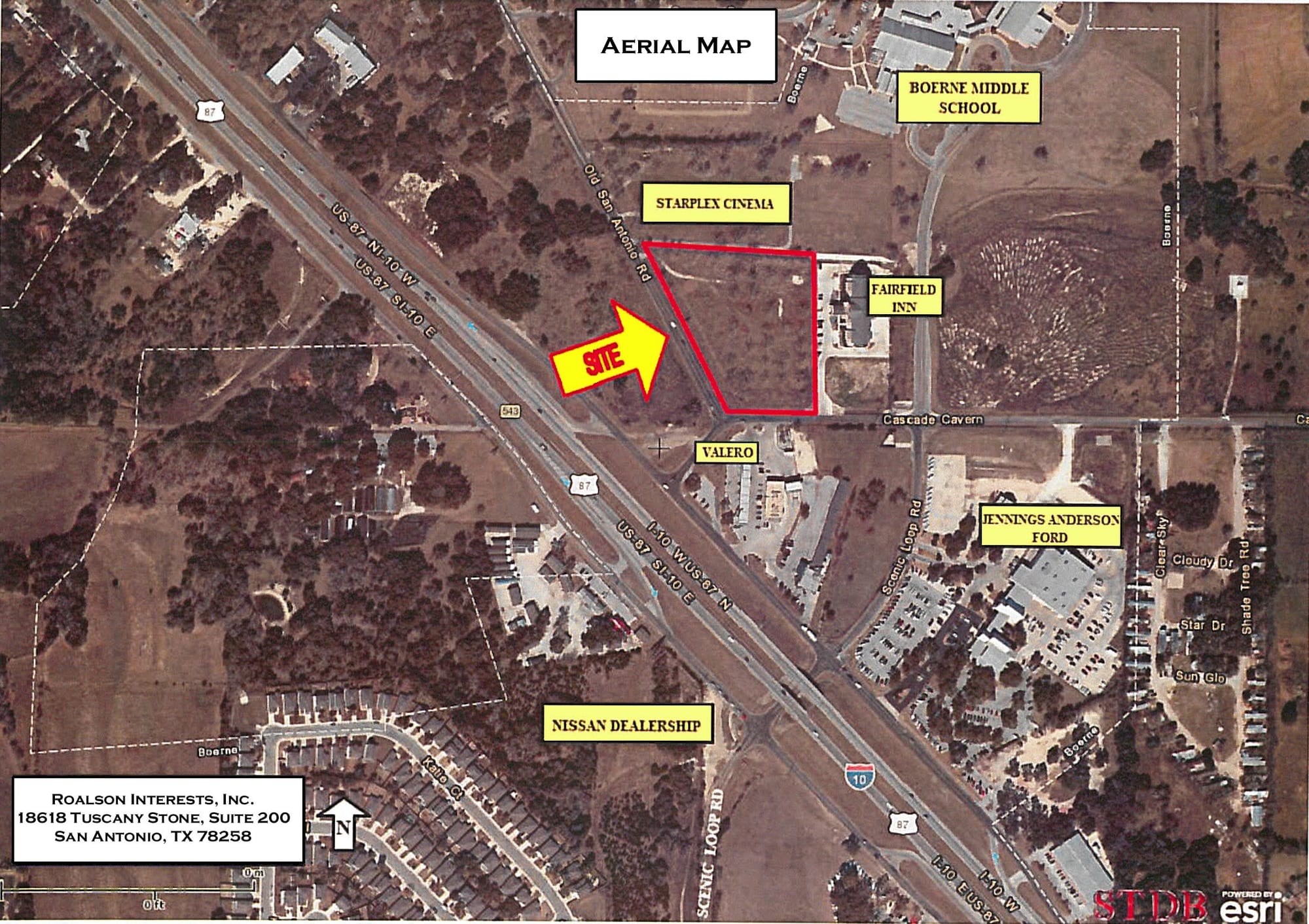 Aerial view of a cleared corner at Cascade Caverns Road and Old San Antonio Road outlined in red, between a cinema and a hotel on the Interstate 10 frontage