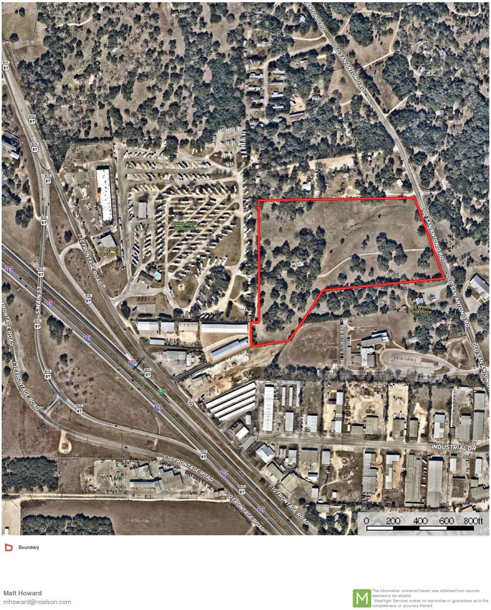 Aerial view of wooded acreage in Boerne with its boundary outlined in red, beside an RV storage yard and the Interstate 10 frontage road