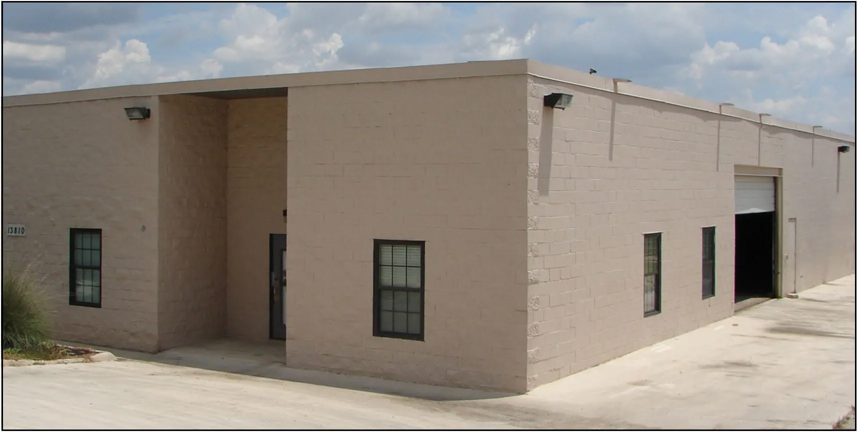 Single-storey masonry office and warehouse building with a roll-up door and a concrete apron