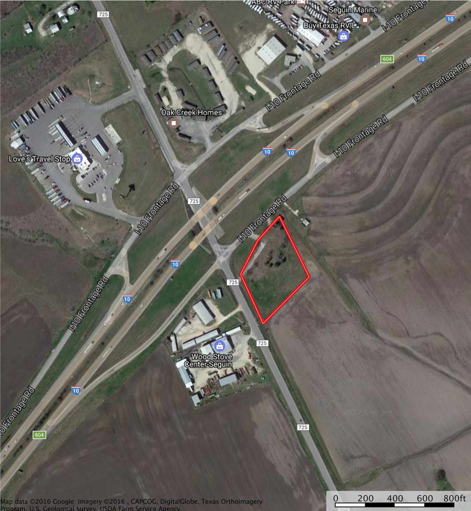 Aerial view of a wedge of open ground outlined in red at the Interstate 10 frontage road and FM 725 in Seguin, across from a truck stop