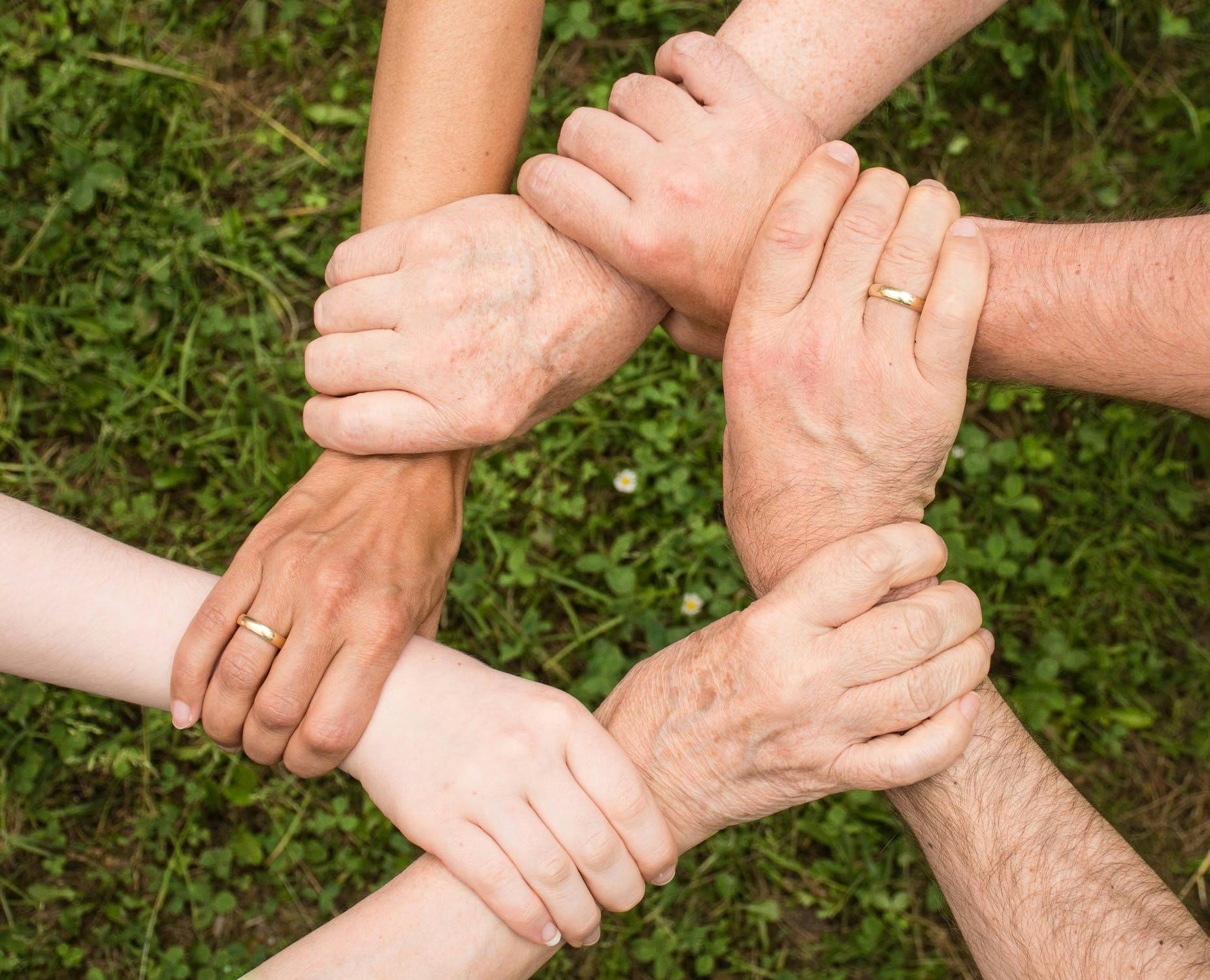 Six people holding their hands forming a circle
