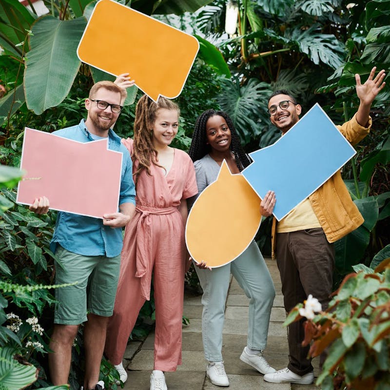 Four people holding cardboard thought bubbles