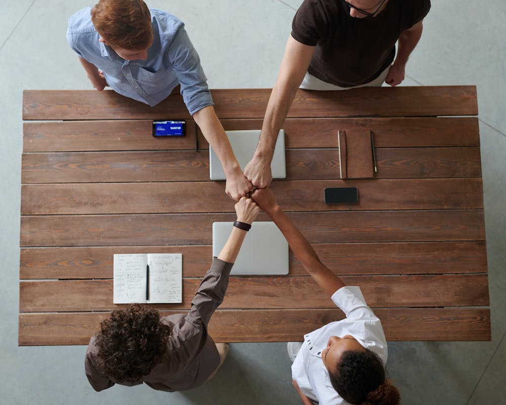Four people fist bumping across a table