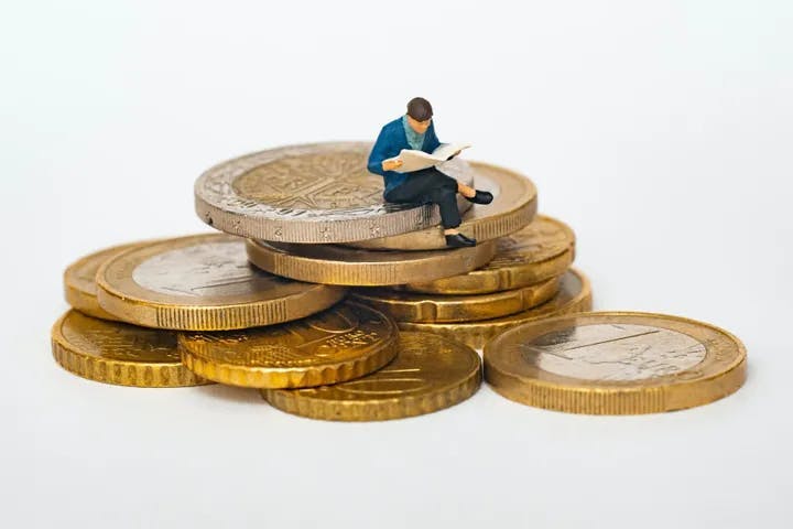 tiny person sitting on a pile of money