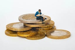 tiny person sitting on a pile of money
