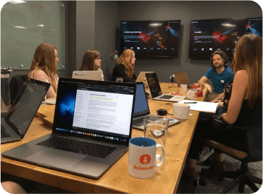 photo of a group of people at a table looking at laptops