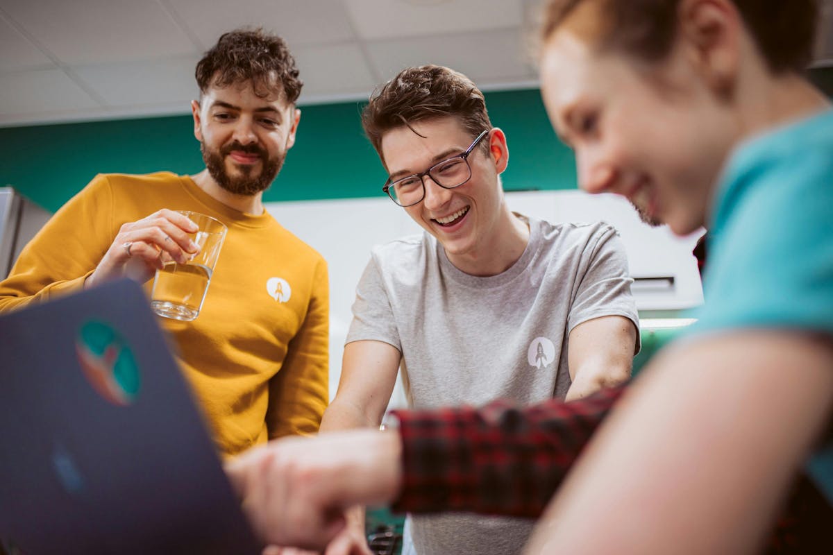 Photo of three Rocketmakers team members smiling looking at a screen.