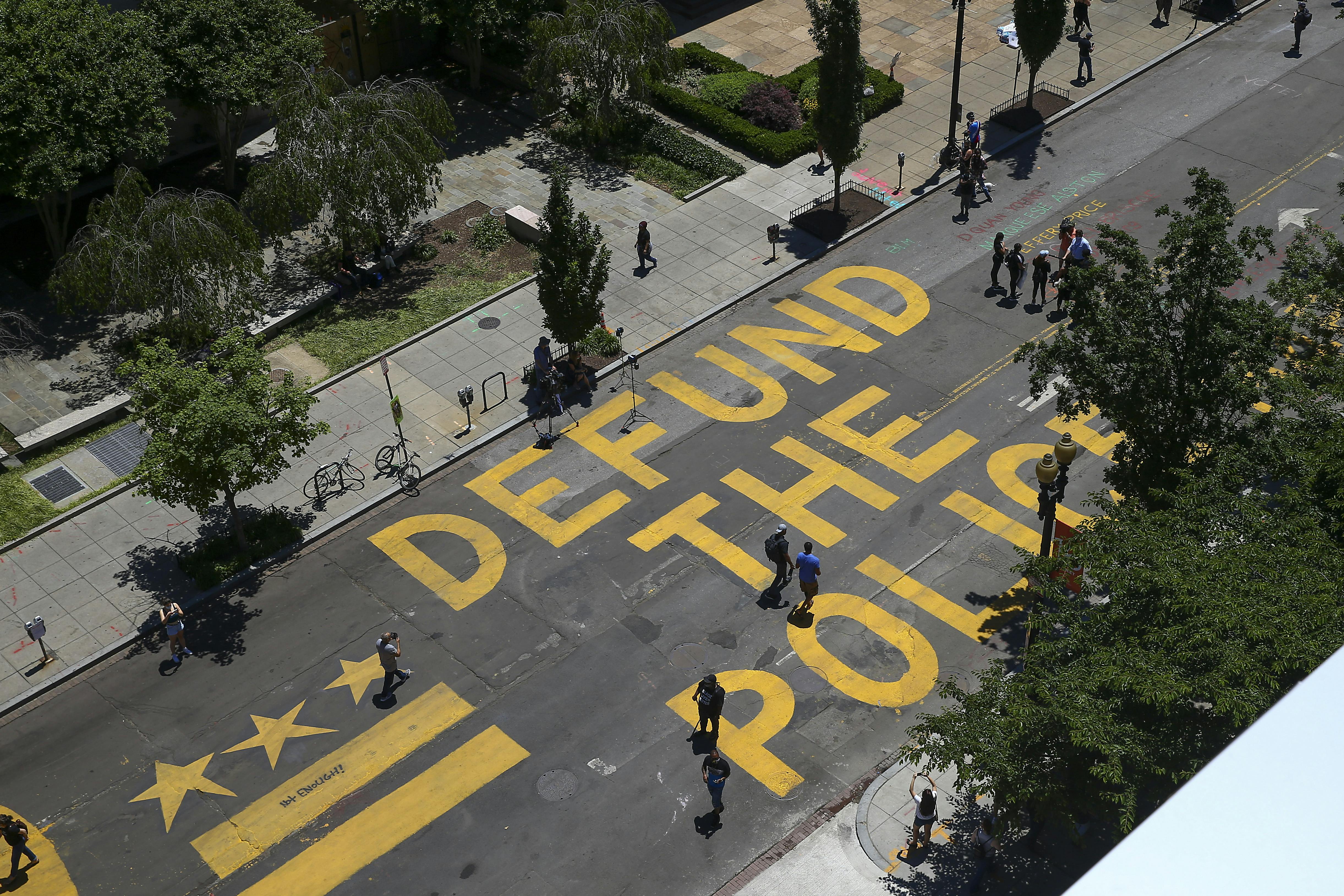 People walk down 16th street after “Defund The Police” was painted on the street near the White House on June 08, 2020 in Washington, DC. After days of protests in DC over the death of George Floyd, DC Mayor Muriel Bowser has renamed that section of 16th street "Black Lives Matter Plaza".