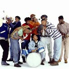 Group portrait of members of the Native Tongues Posse rap collective as they clown around with toy instruments, New York, New York, 1990. Among those pictured are members of the individual groups De La Soul, a Tribe Called Quest, and the Jungle Brothers; this image was taken during the photo shoot for the latter's 'Doin' Our Own Dang' single. Pictured are, from left, DJ Red Alert, Q-Tip, Ali Shaheed Muhammad, Mike Gee (in red), Monie Love (at drums), Afrika Baby Bam, Maseo, and Posdnuos.