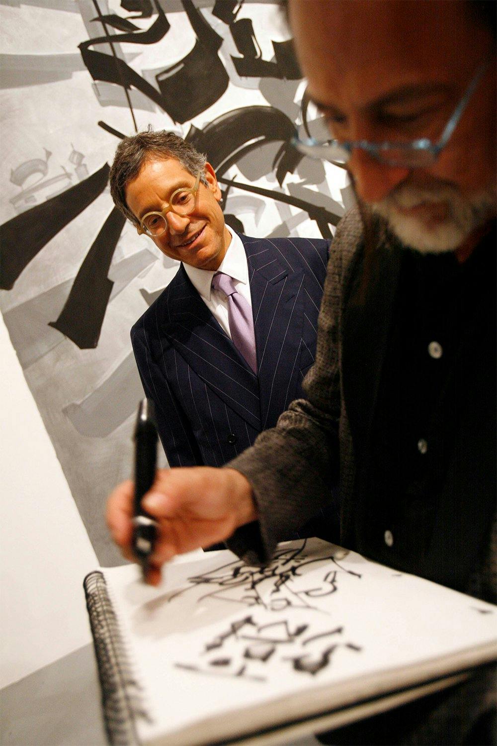 MOCA director Jeffrey Deitch, left, watch as artist Chaz Bojorquez draws on a pad during the member's reception of 