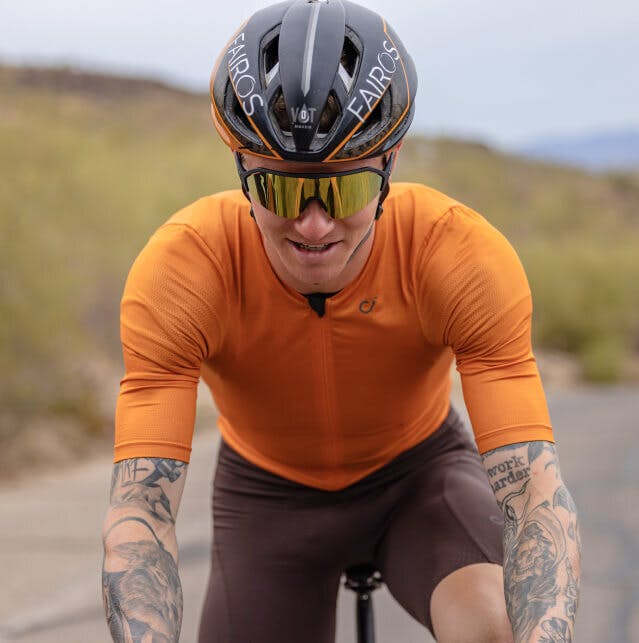 Man in orange bike suit and black helmet wearing San Remo sunglasses