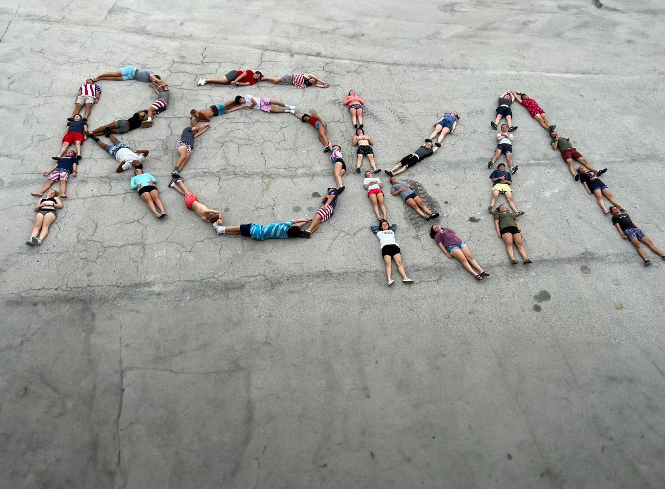 People laying on the ground in the shape of a ROKA logo