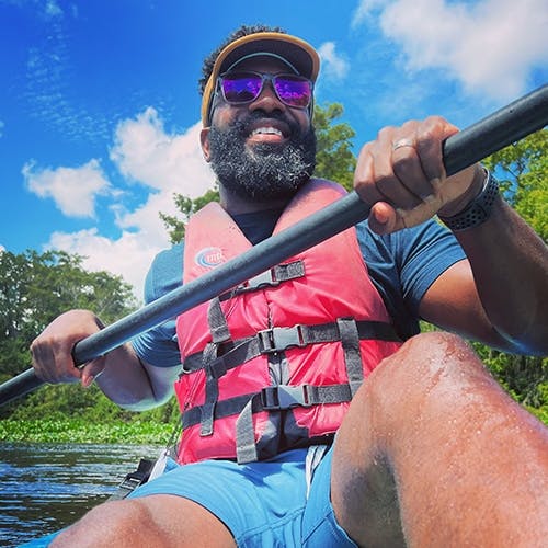 Man kayaking in red lifejacket 