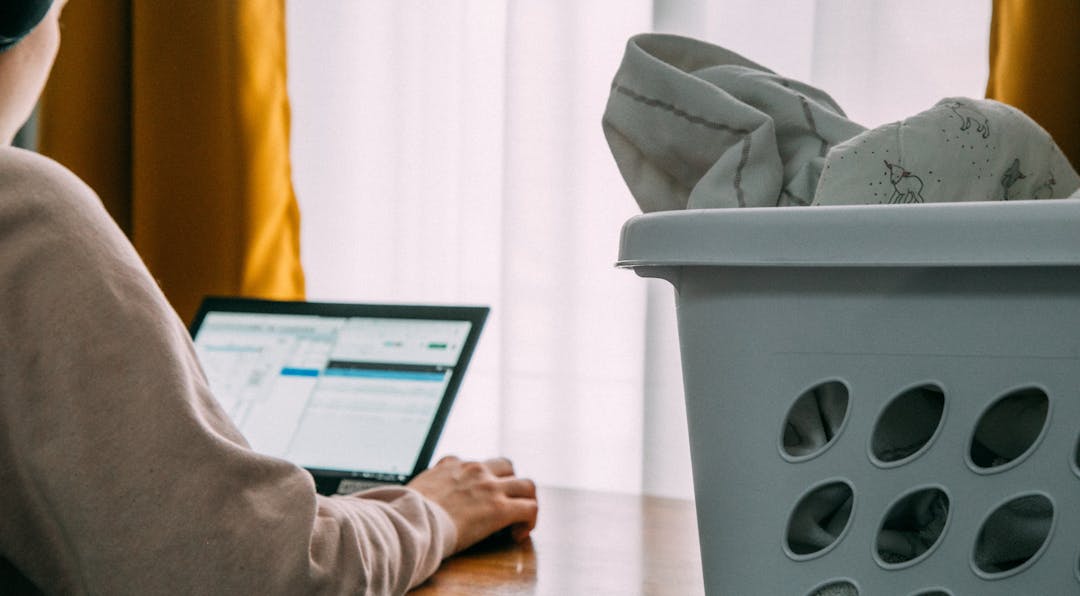 A woman working from her home office with washing to be folded beside her