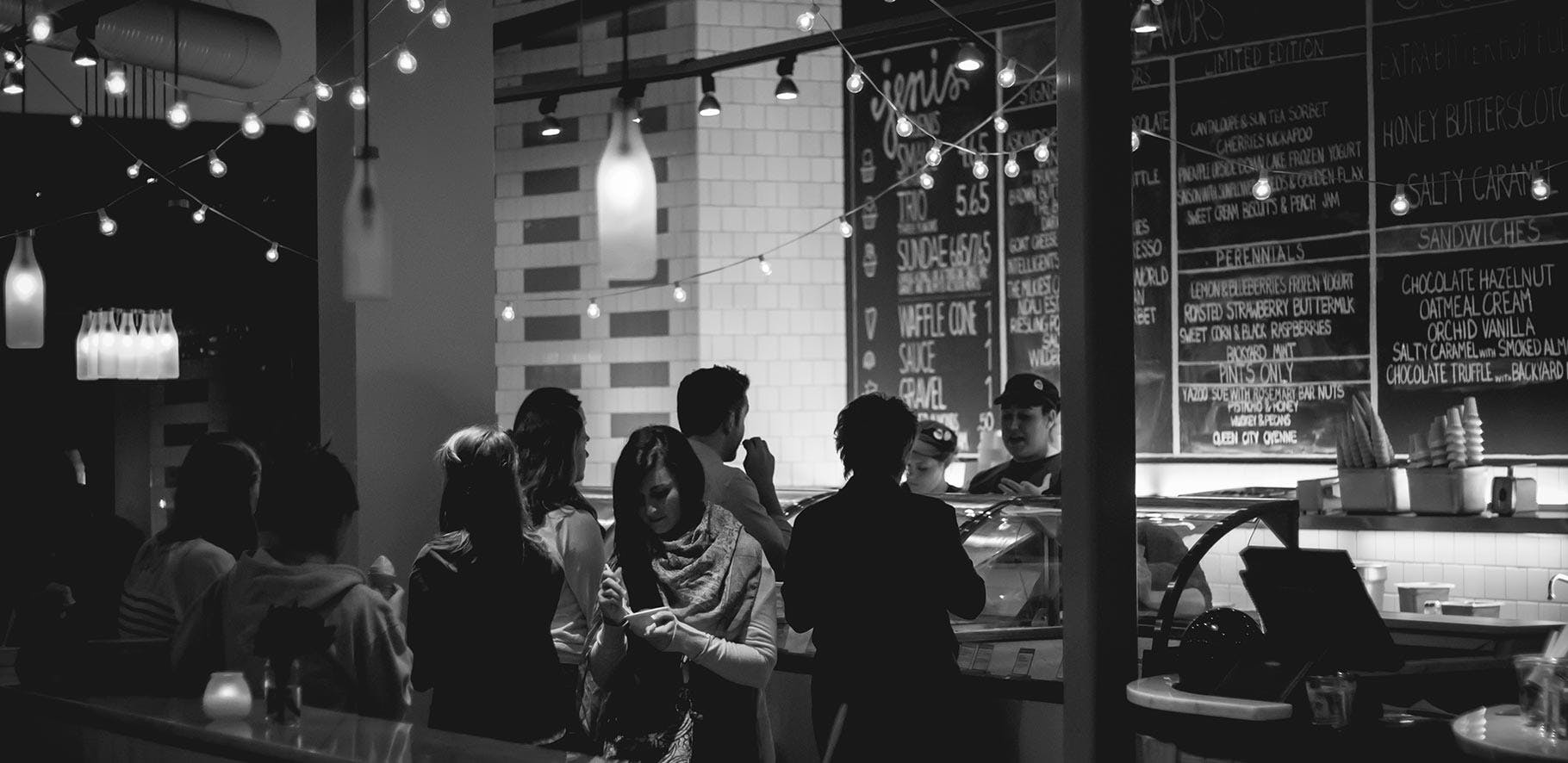 moody black and white image of a group of people ordering food from a cafe