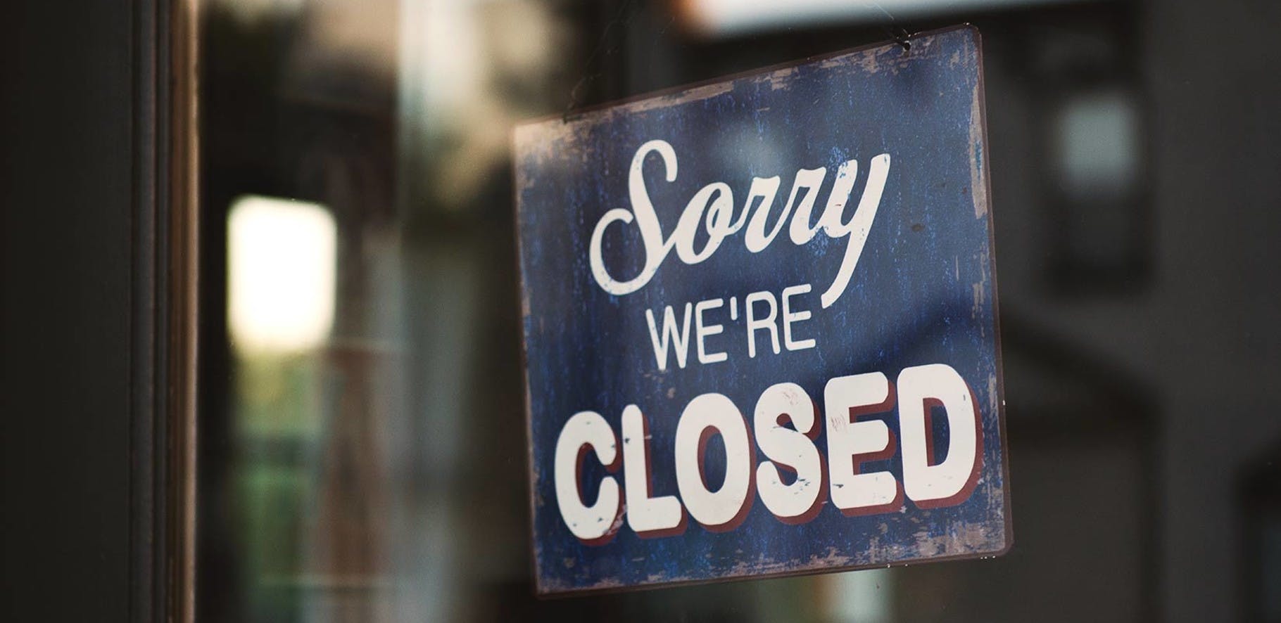 retro sign hanging in the doorway of a business saying sorry we're closed