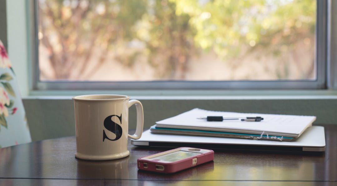 coffee cup and phone with project management papers on table