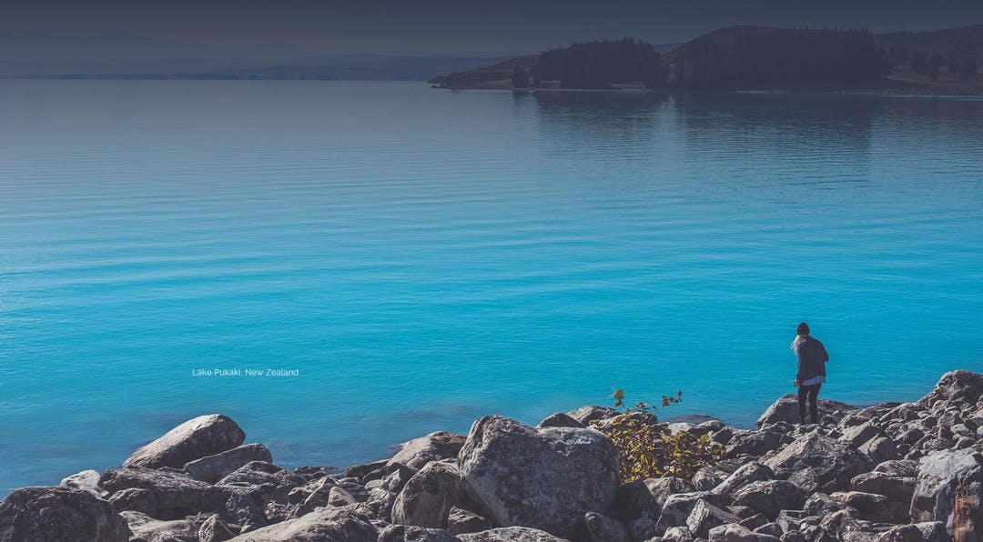 Women walking down some rocks to the edge of a beautiful blue lake