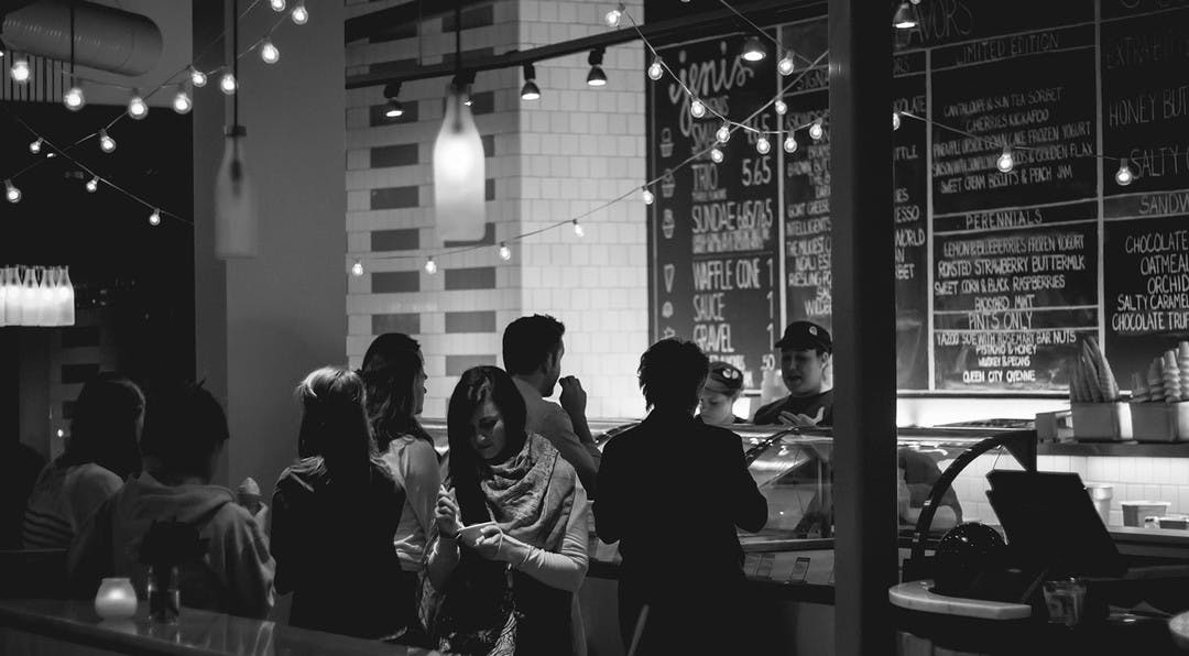 moody black and white image of a group of people ordering food from a cafe