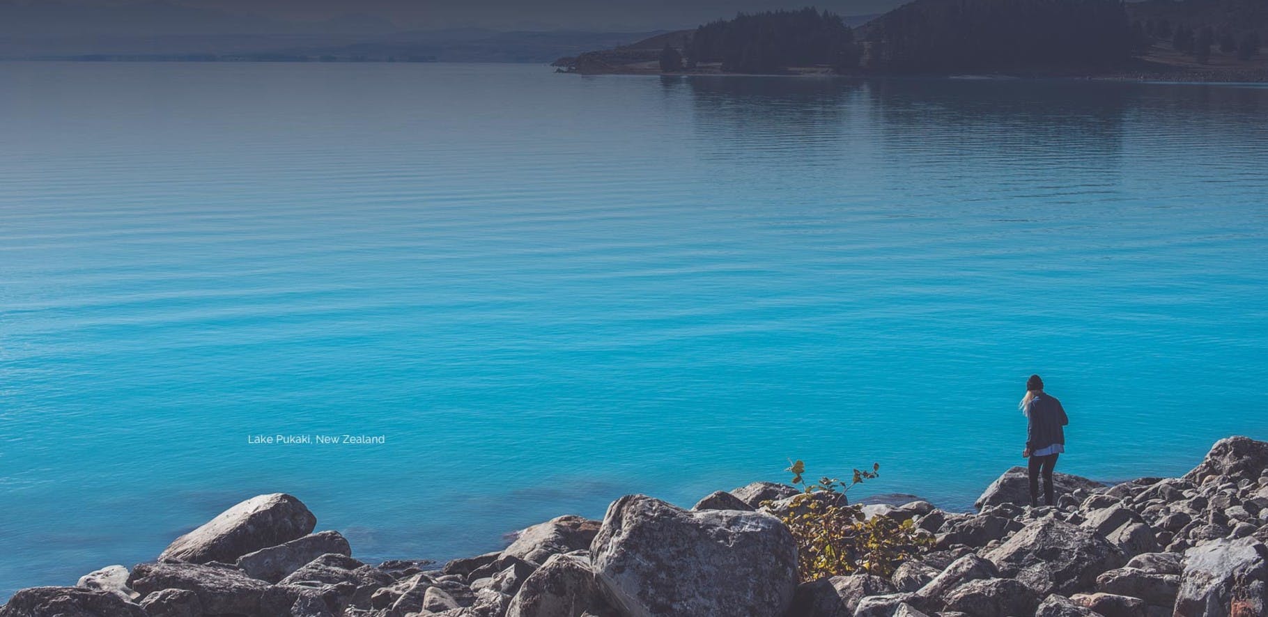 Women walking down some rocks to the edge of a beautiful blue lake