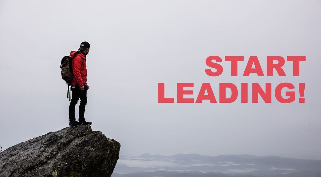 Tramper with a backpack on standing on the edge of a rock over looking a valley