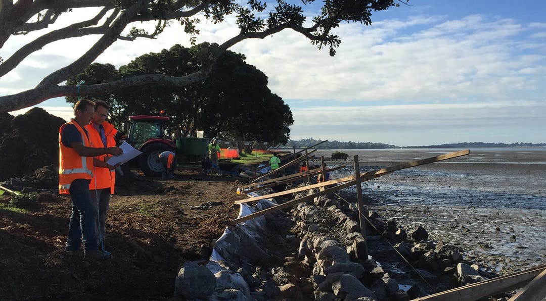 construction people in the progress of fixing a sea wall looking at plans