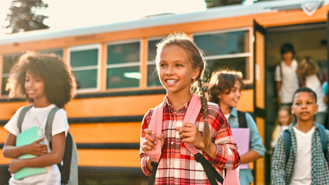 Children with backpacks exiting a yellow school bus, highlighting student transportation and safety