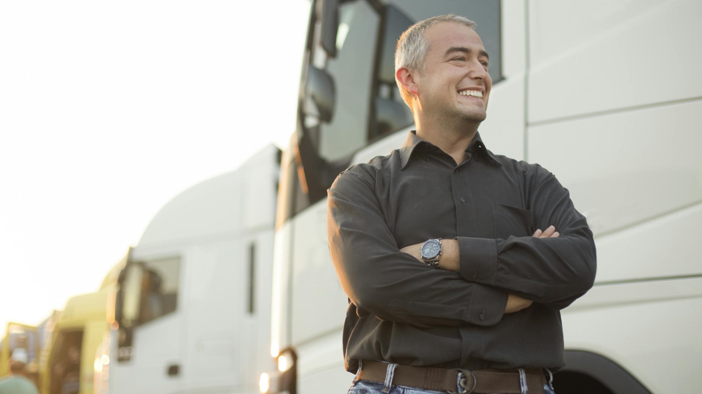 Person standing confidently in front of a white truck, highlighting commercial vehicle safety.