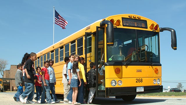 Students boarding yellow school bus #268 with American flag in background, promoting safe school transportation.