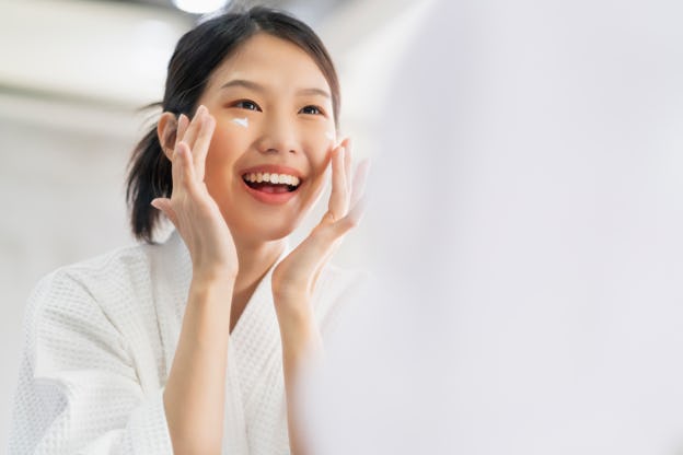 Woman applying cream to her face.
