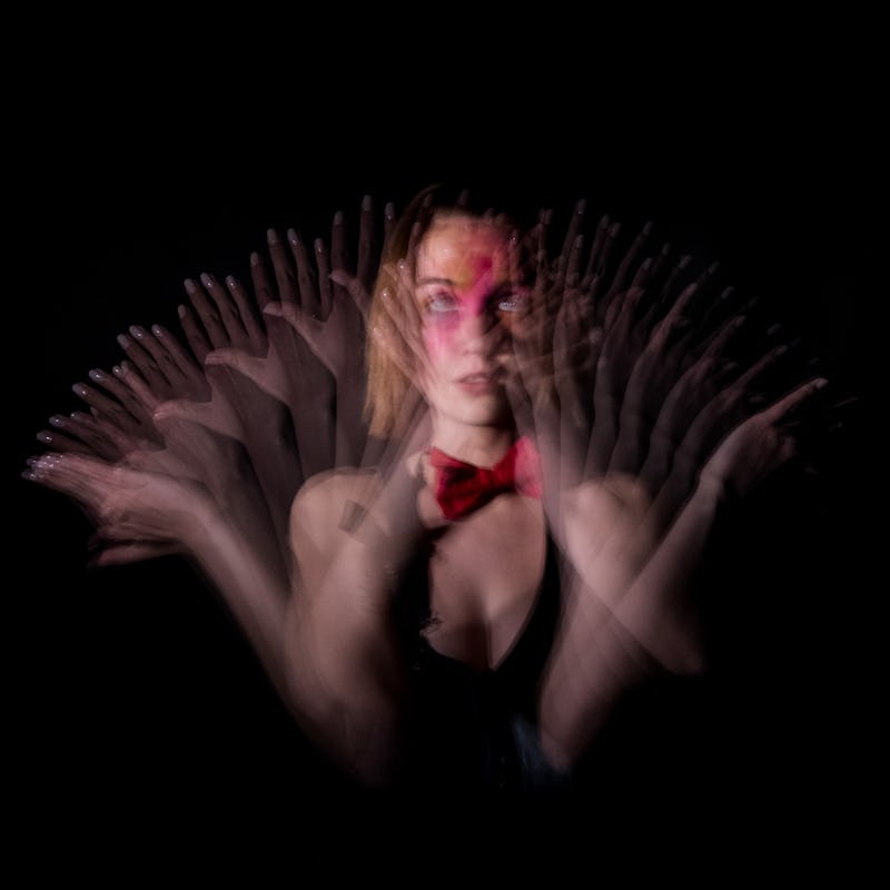 Woman waving her hands in blur against a black background.