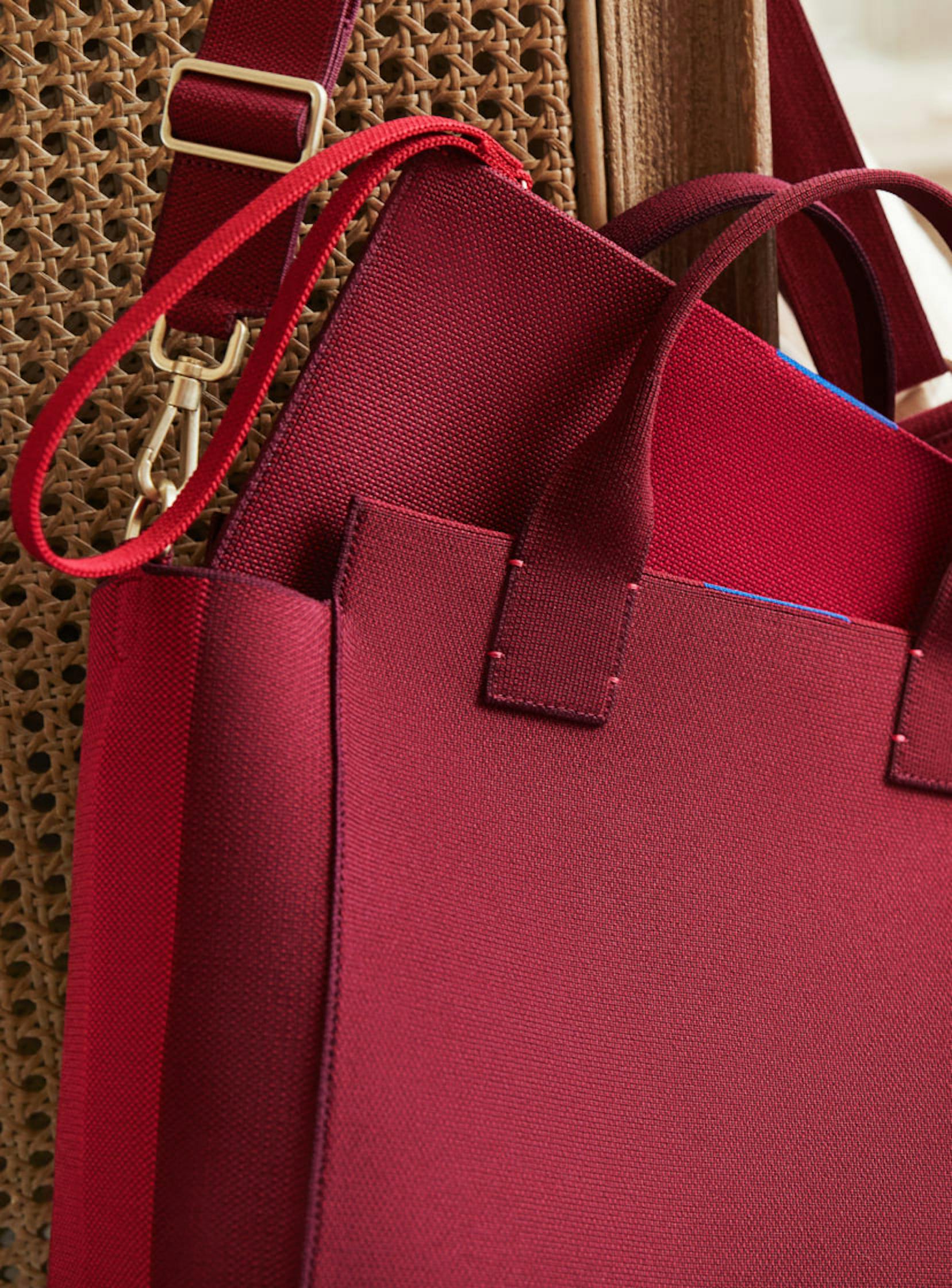 Close up of The Bucket Bag in Ruby Red with The Essential Pouch in Ruby Red peeking out.