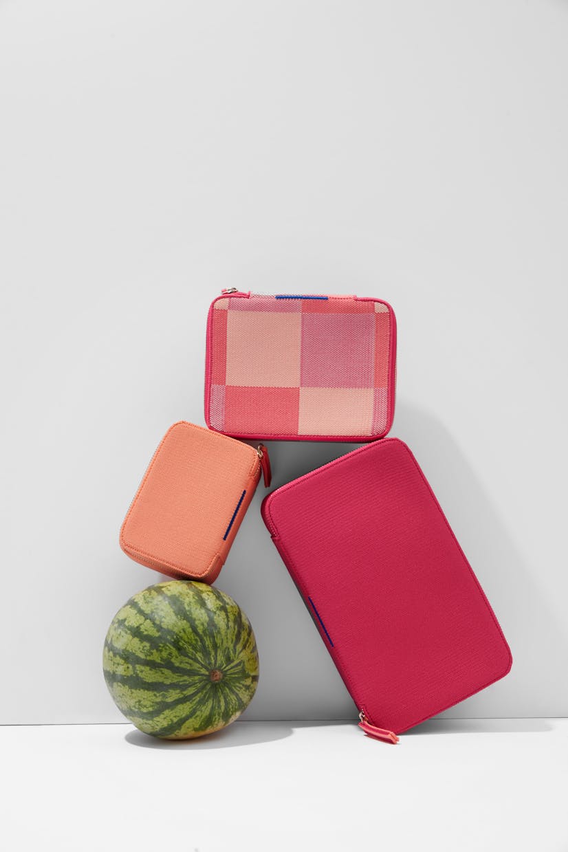 The Mini Catchall in Light Melon, The Mid Catchall in Peach Madras and The Large Catchall in Bright Fuchsia shown balanced with a watermelon.