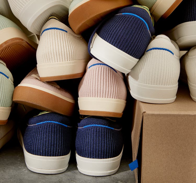 A stack of The Lace Up in Navy, Lilac, Vanilla, Bright White and Spearmint, shown from the back with halo detail on heel.