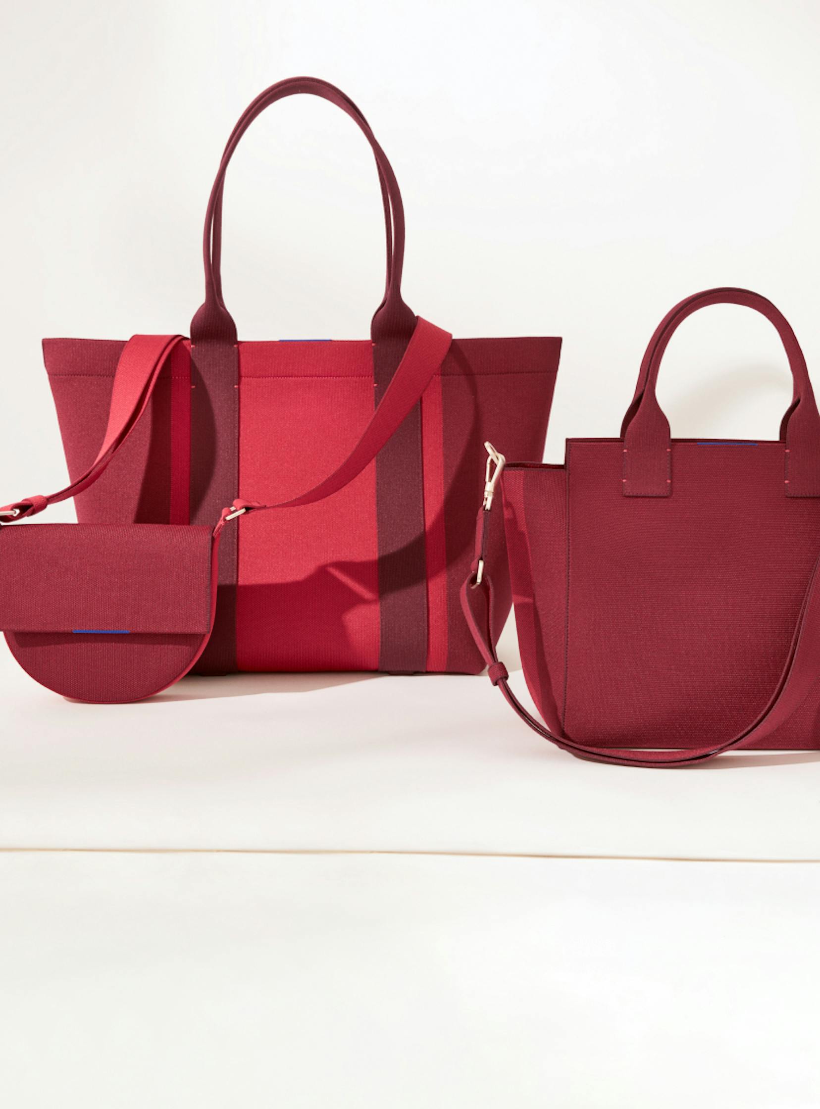 The Saddle Bag in Ruby Red, The Essential Tote in Ruby Red and The Handbag in Ruby Red shown from left to right.