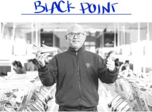 Black and white image of a member of the Rothy’s team holding a shoe. 