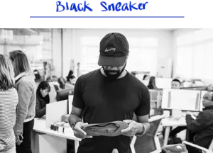 Black and white image of a member of the Rothy’s team holding a shoe. 