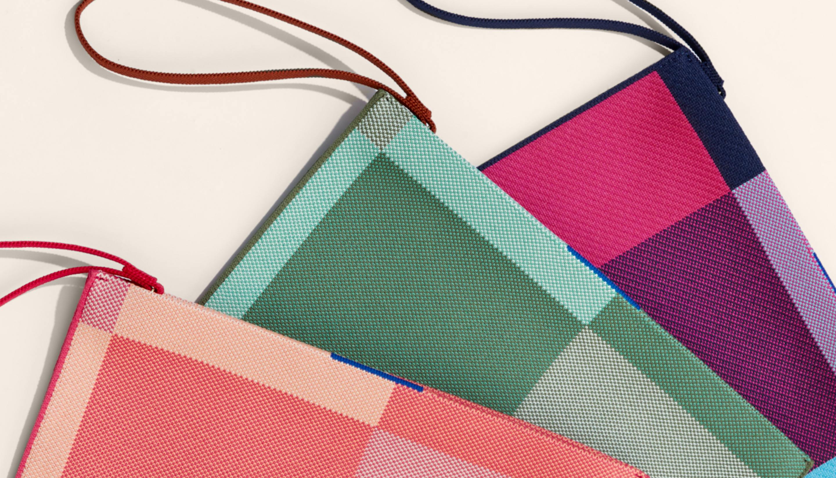 Close up image of The Essential Pouch in Peach Madras, The Essential Pouch in Juniper Madras and The Essential Pouch in Neon Madras.