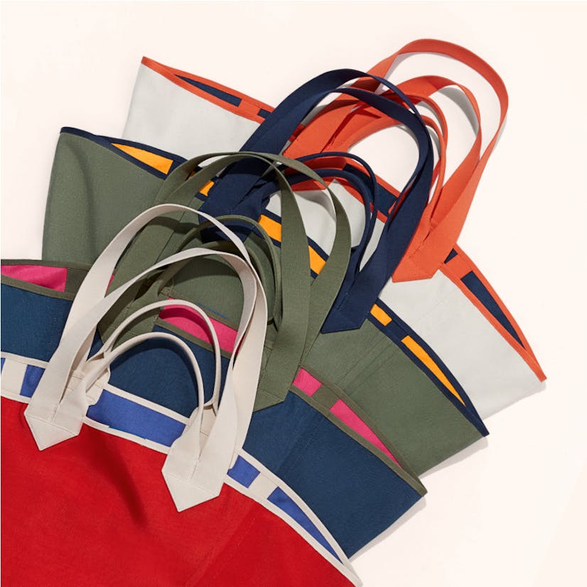 The Reversible Tote in Red & Cobalt, The Reversible Tote in Navy & Pink, The Reversible Tote in Olive & Yellow, The Reversible Tote in White & Navy shown in a laydown.