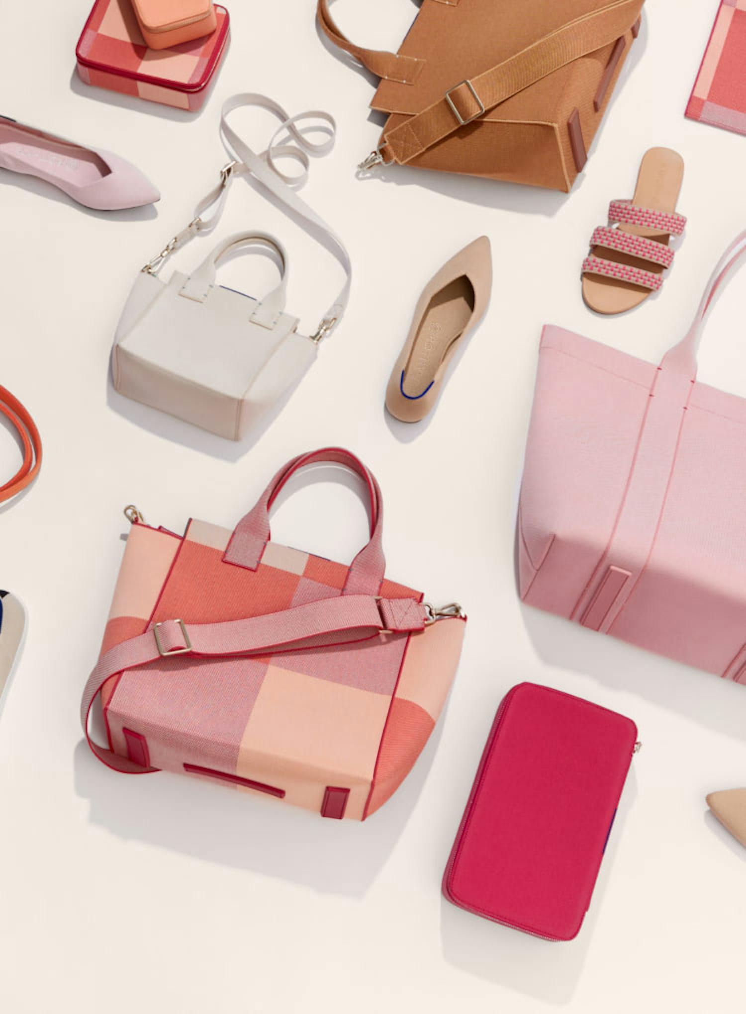 A laydown featuring The Point in Blush, The Point in Ecru, The Triple Band in Hot Pink Basket Stitch, The Knot in Candy Apple, The Mid Catchall in Peach Madras, The Mini Catchall in Light Melon, The Handbag in Sienna Brown, The Essential Pouch in Peach Madras, The Essential Tote in Rose Water, The Handbag in Peach Madras, The Mini Handbag in Sea Salt and The Large Catchall in Bright Fuchsia.