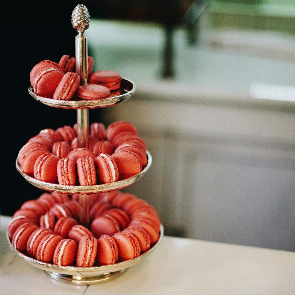 Rose macarons shown on a silver tiered platter.