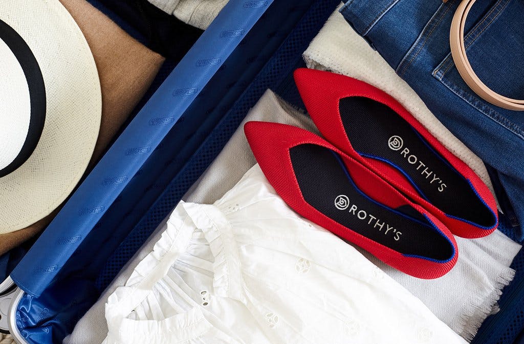 A close up of folded clothes and red Rothy's flats in a luggage. 